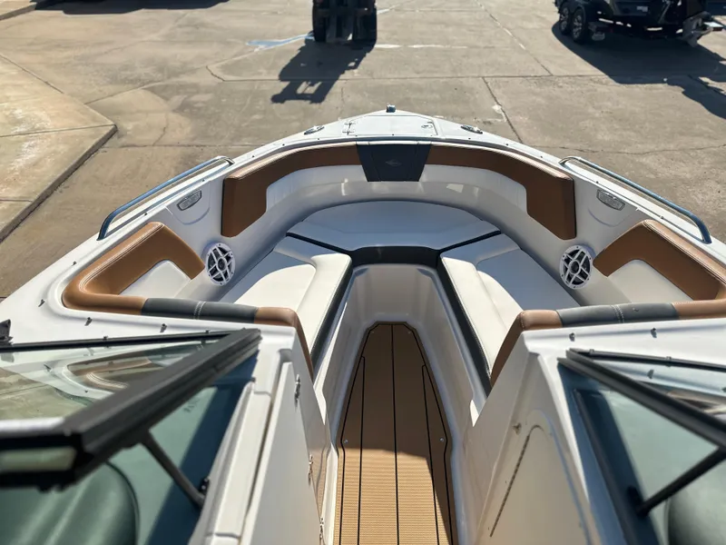 Slide: The Image of 2025 Chaparral 23 SSi boat interior with tan and white seating, docked outdoors. - 6