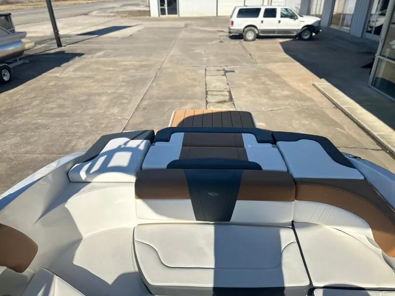 Slide: The Image of 2025 Chaparral 23 SSi boat interior with white and brown seating, parked outdoors. - 8
