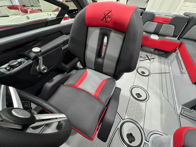 Slide: The Image of 2025 MasterCraft X24 interior with red and gray seating, modern steering, and sleek design. - 12