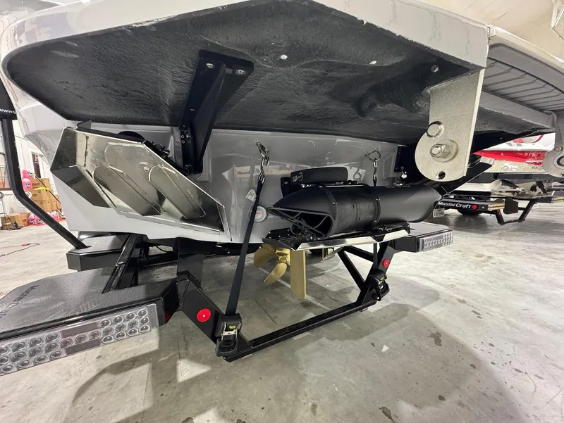 Slide: The Image of 2025 MasterCraft X24 boat underside showing propeller and exhaust system in a garage. - 3