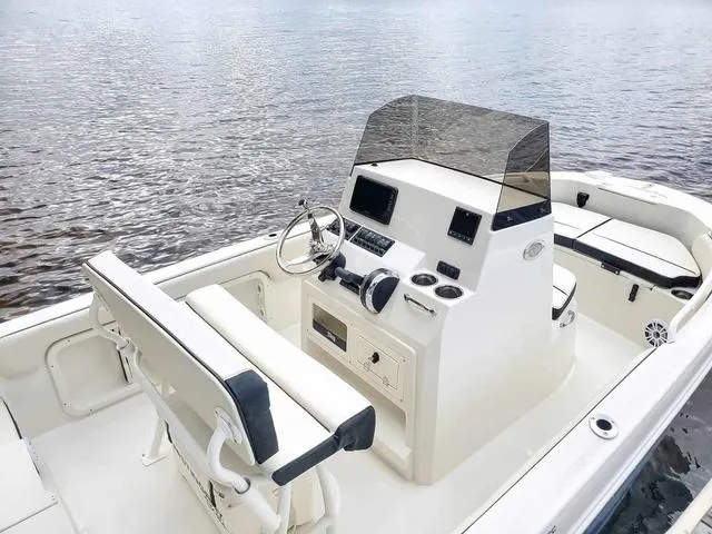 Slide: The Image of 2023 Stingray 173 CC boat interior with steering console, seating, and water backdrop. - 33