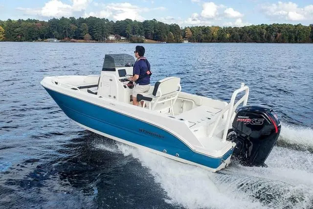Slide: The Image of 2023 Stingray 173 CC boat cruising on a lake with a scenic forest backdrop. - 36