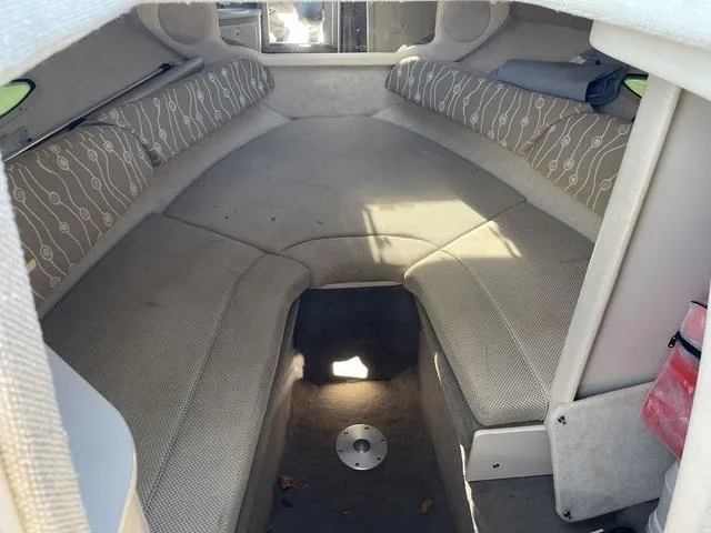 Slide: The Image of 2005 Sea Ray 225 Weekender cabin interior with cushioned seating and storage. - 20