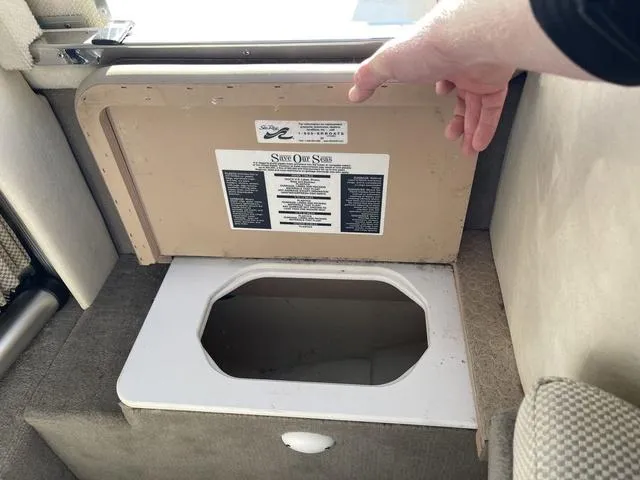 Slide: The Image of 2005 Sea Ray 225 Weekender storage compartment with open lid, showcasing interior space. - 25