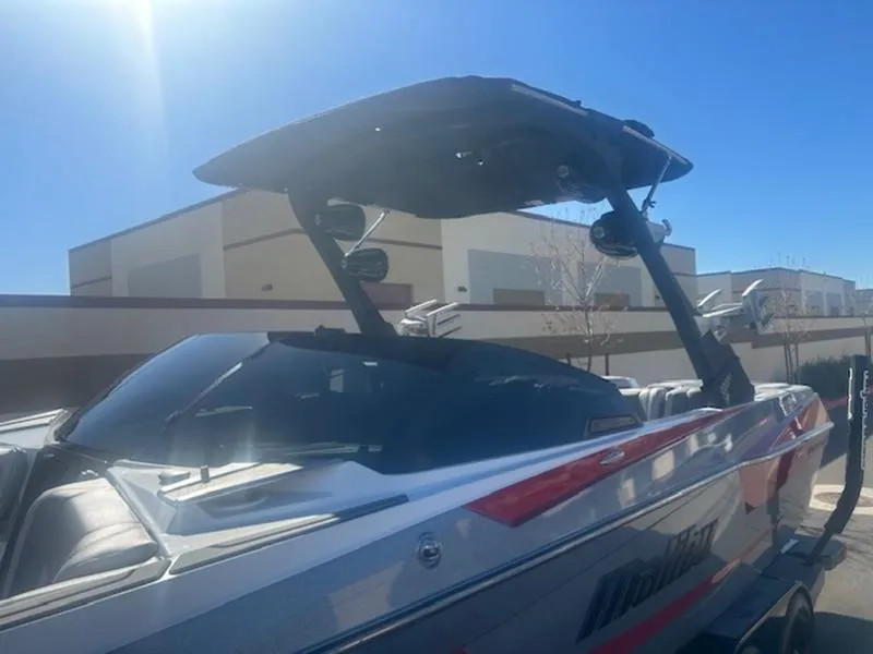 Slide: The Image of 2021 Malibu 23 MXZ boat with sleek design, parked outdoors under clear blue sky. - 6
