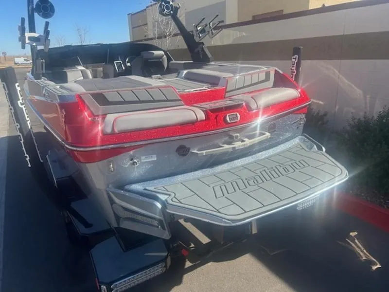 Slide: The Image of 2021 Malibu 23 MXZ boat, rear view, red and gray, parked outdoors. - 7