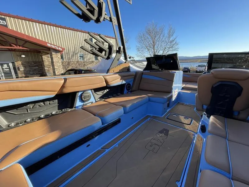 Slide: The Image of 2024 Axis A245 boat interior with tan and blue seating, docked near a building. - 10