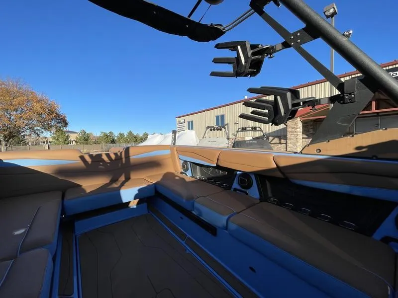 Slide: The Image of 2024 Axis A245 boat interior with brown seating and blue accents under clear sky. - 11