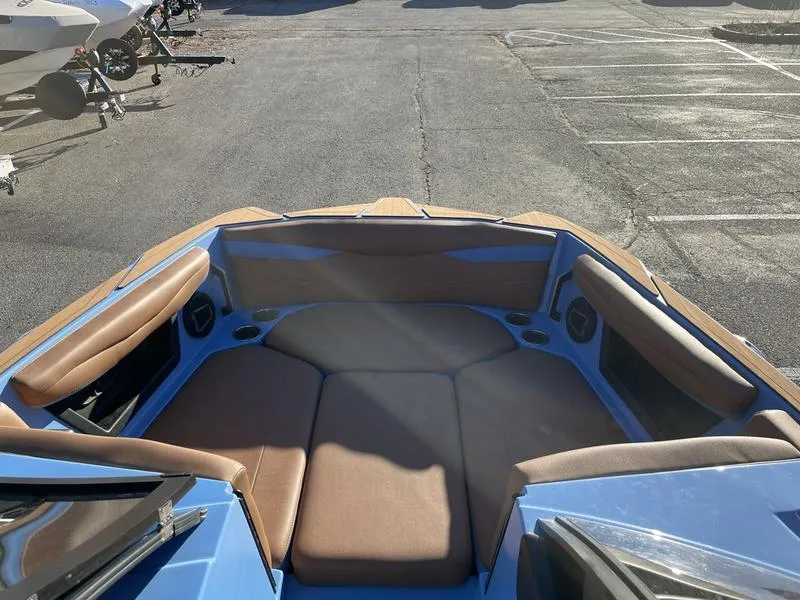 Slide: The Image of 2024 Axis A245 boat interior with brown seating and blue accents in a parking lot. - 14