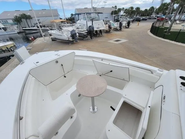 Slide: The Image of 2016 Sea Hunt Edge 24 boat interior with open storage compartments and table, docked at marina. - 22