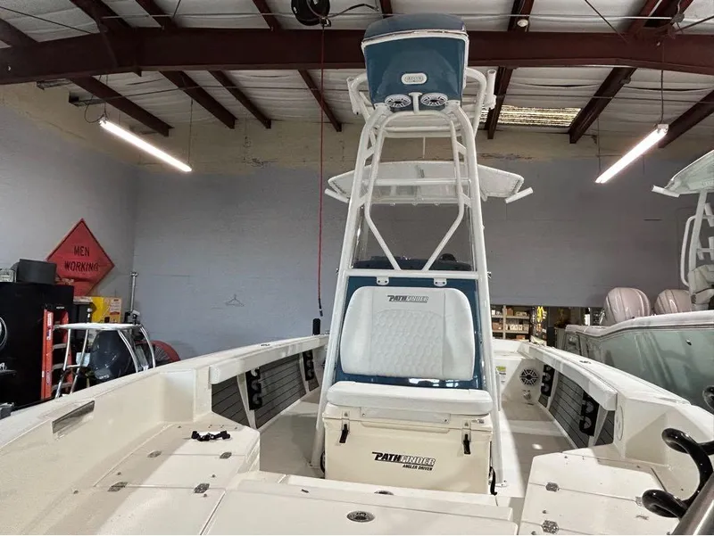 Slide: The Image of 2025 Pathfinder 2400 TRS boat in a garage, featuring a center console and T-top. - 3