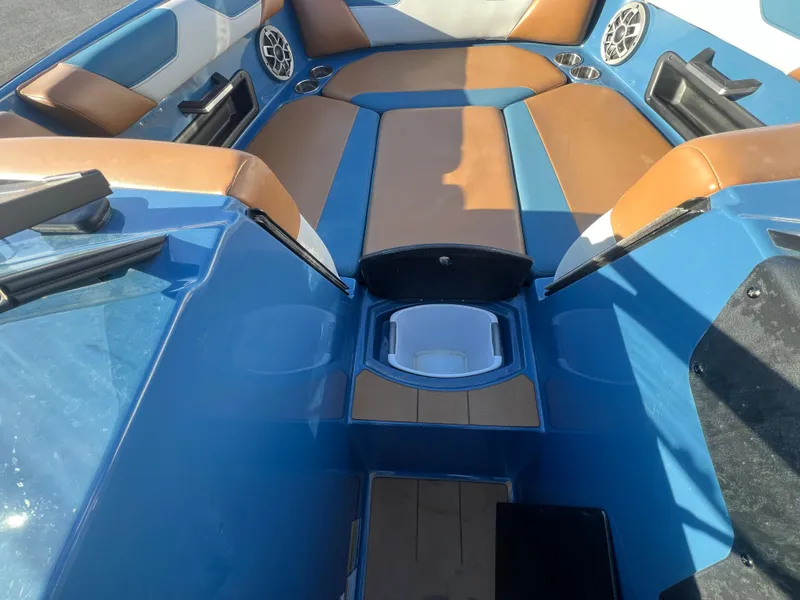 Slide: The Image of 2022 Axis Wake Research A24 boat interior with blue and brown seating, cup holders, and speakers. - 20