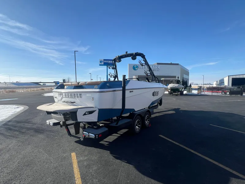 Slide: The Image of 2022 Axis Wake Research A24 boat on trailer in parking lot, clear sky background. - 5