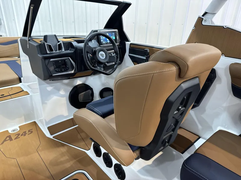 Slide: The Image of 2025 Axis A245 boat interior with tan and navy seating, modern dashboard, and steering wheel. - 10