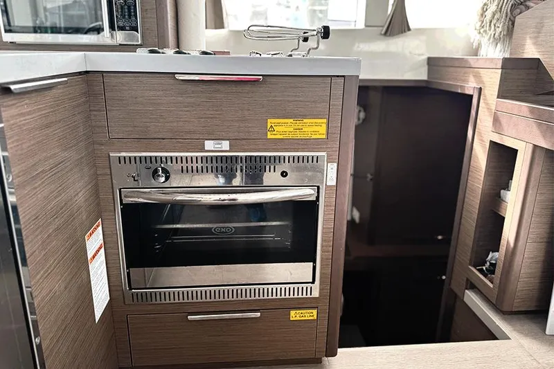 Slide: The Image of Modern kitchen inside 2019 Lagoon 40 catamaran with built-in oven and wooden cabinetry. - 16