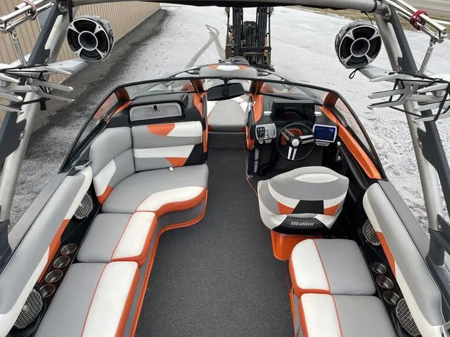 Slide: The Image of 2016 Malibu 22 VLX boat interior with orange and gray seating, modern dashboard, and speakers. - 10