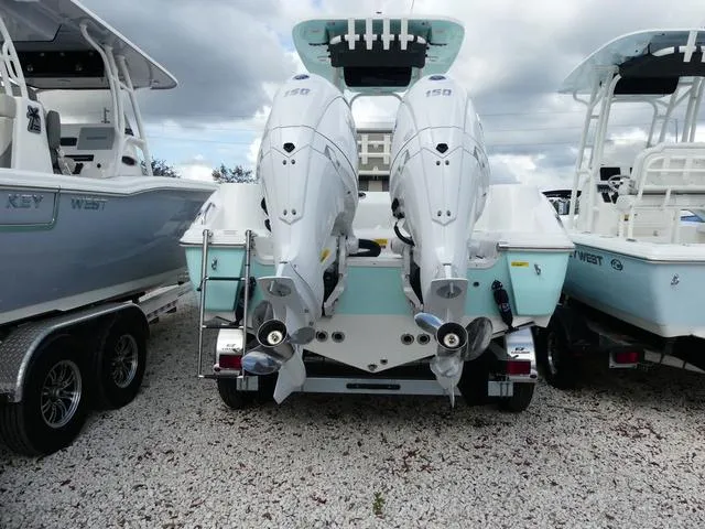 Slide: The Image of 2025 Key West 244 CC boat with dual outboard engines, parked on gravel. - 6