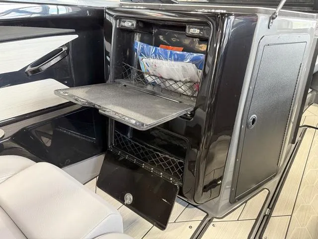 Slide: The Image of 2025 Yamaha Boats 222XE interior storage compartment with open shelves and documents. - 16