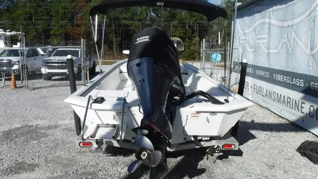 Slide: The Image of 2021 Avid 23 FS boat with outboard motor, parked on gravel lot. - 4