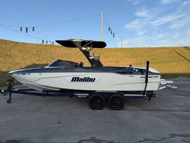Slide: The Image of 2021 Malibu 25 LSV boat on trailer, parked outdoors under clear sky. - 17