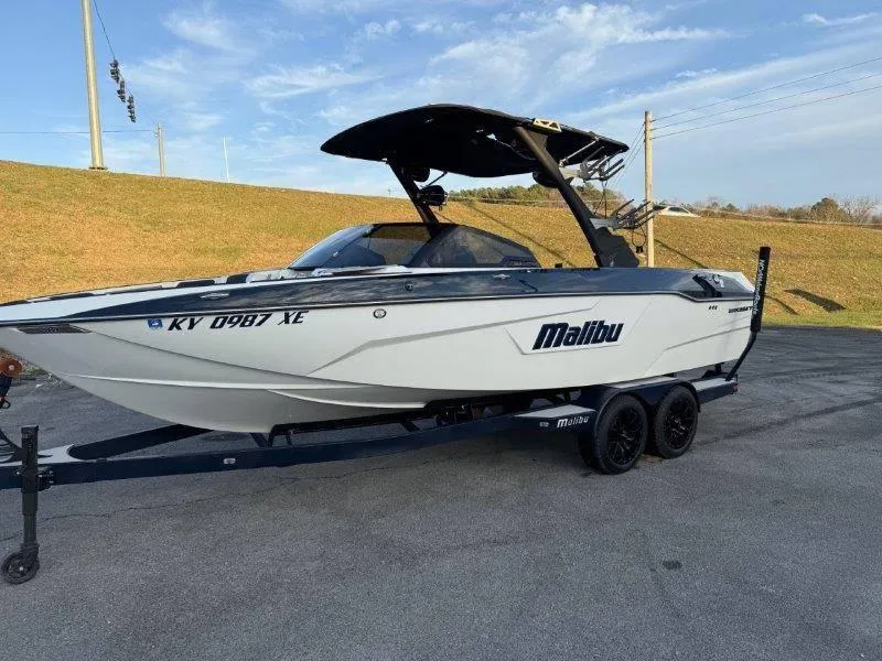 Slide: The Image of 2021 Malibu 25 LSV boat on trailer, parked outdoors under clear sky. - 21