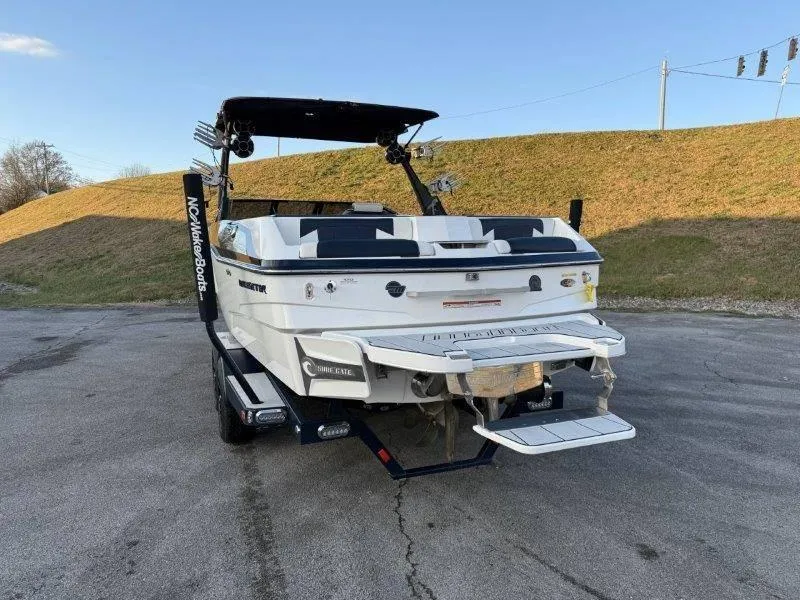 Slide: The Image of 2021 Malibu 25 LSV boat with swim platform, parked on pavement. - 22