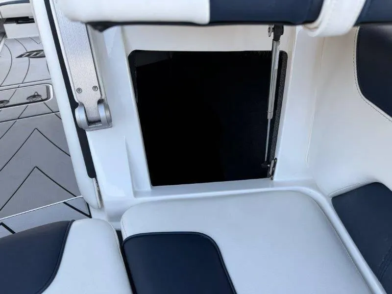 Slide: The Image of 2021 Malibu 25 LSV boat interior storage compartment with cushioned seating. - 28