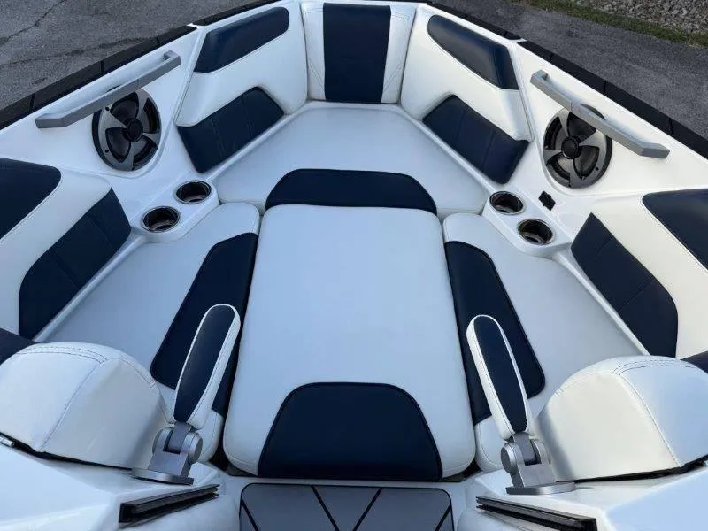 Slide: The Image of 2021 Malibu 25 LSV boat interior with white and navy seating, cup holders, and speakers. - 29