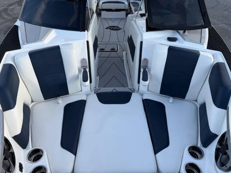 Slide: The Image of 2021 Malibu 25 LSV boat interior with white and navy seating, cup holders, and sleek design. - 32
