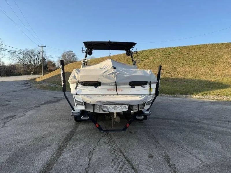 Slide: The Image of 2021 Malibu 25 LSV boat covered and parked on a paved road. - 46