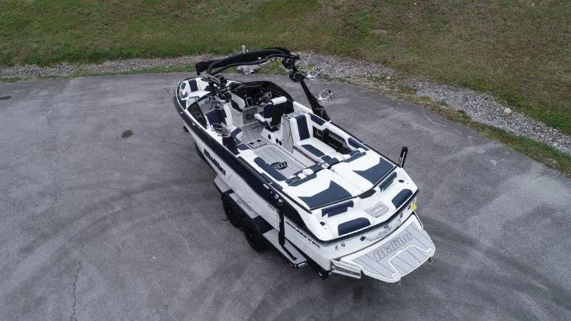 Slide: The Image of 2021 Malibu 25 LSV boat on trailer, aerial view, parked on concrete surface. - 9
