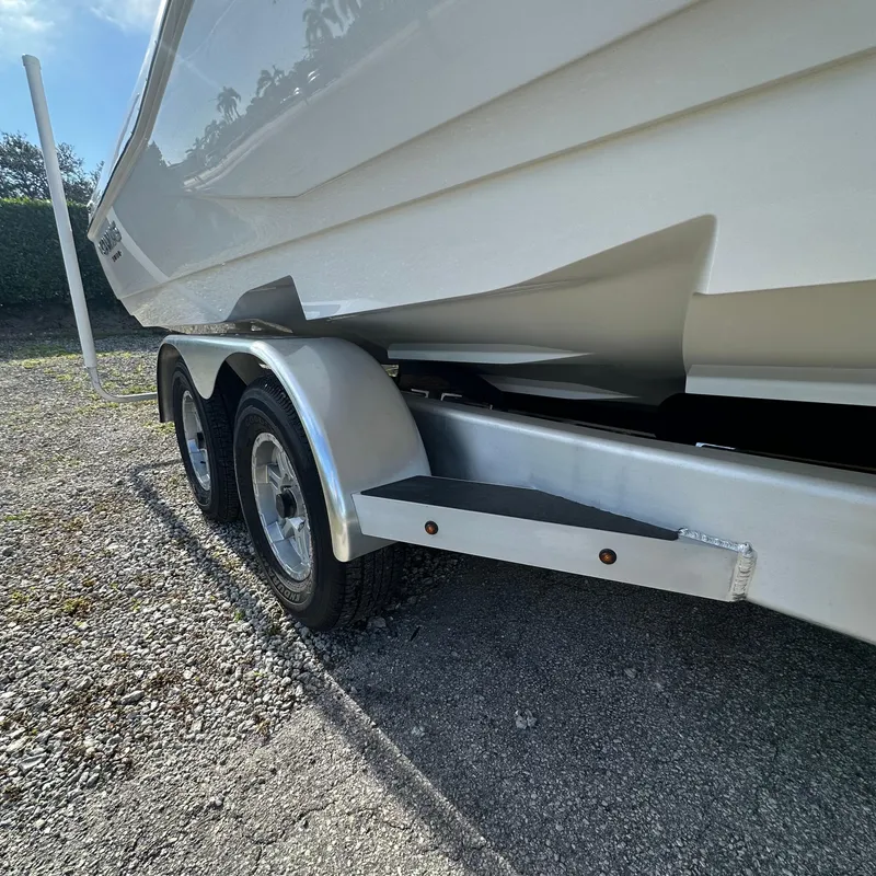 Slide: The Image of 2025 Caymas 28 HB boat on a dual-axle trailer, parked on gravel. - 14