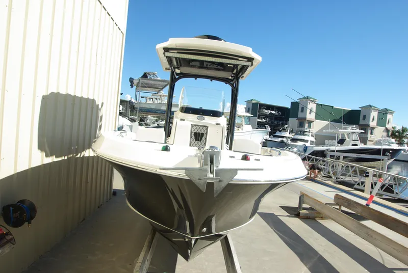 Slide: The Image of 2018 Wellcraft 222 Scarab Offshore boat docked at marina under clear blue sky. - 2
