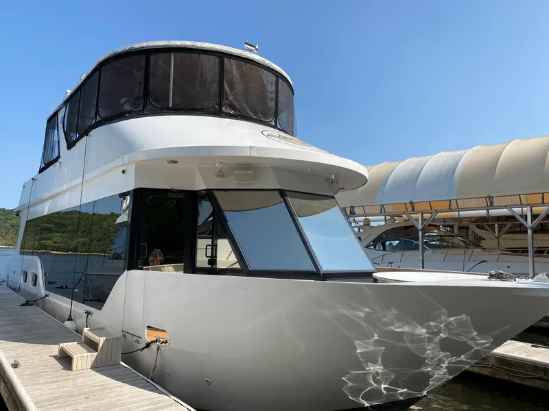 Slide: The Image of 2005 Skipperliner Millenium houseboat docked on a serene lake under a clear blue sky. - 2