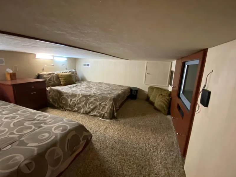 Slide: The Image of 2005 Skipperliner Millenium interior with two beds, modern lighting, and cozy carpeted flooring. - 20