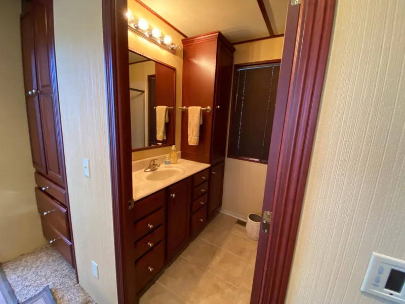 Slide: The Image of Interior of 2005 Skipperliner Millenium with wooden cabinets and cozy bedroom decor. - 30