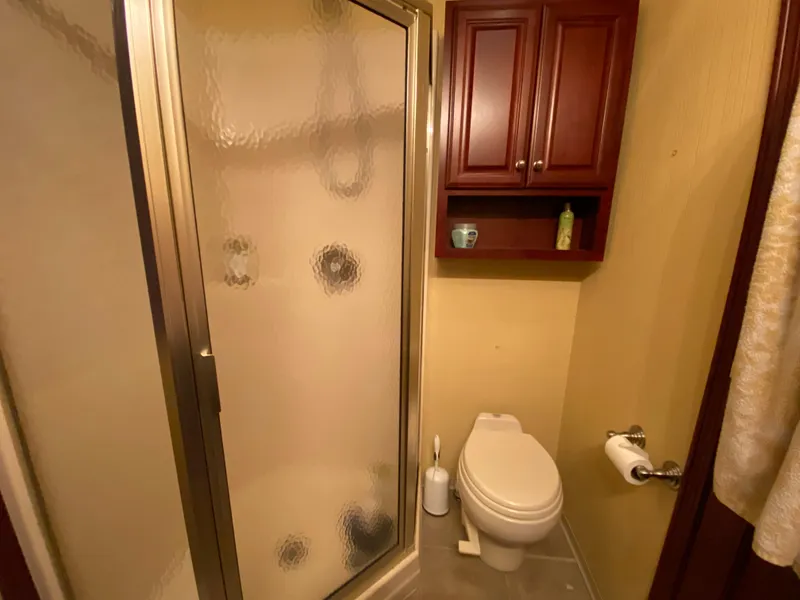 Slide: The Image of Bathroom interior of 2005 Skipperliner Millenium with shower, vanity, and wooden cabinetry. - 32