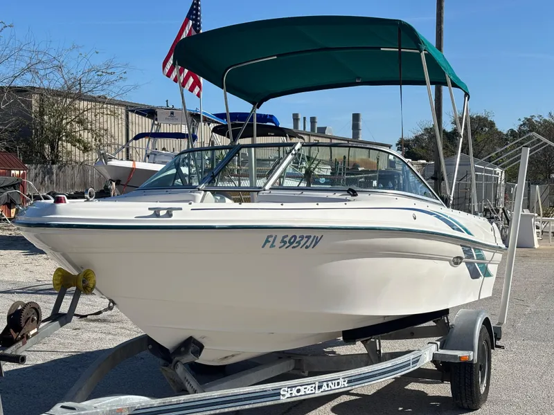Slide: The Image of 1998 Sea Ray 180 Bow Rider boat on trailer with green canopy and American flag. - 11