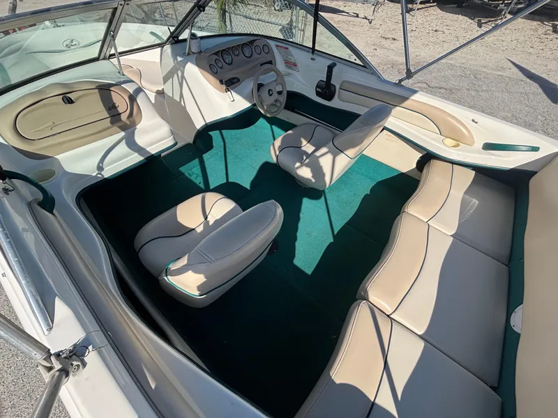 Slide: The Image of 1998 Sea Ray 180 Bow Rider interior with beige seats and green carpet. - 17