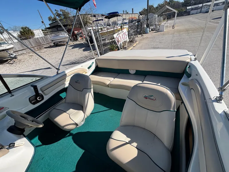 Slide: The Image of 1998 Sea Ray 180 Bow Rider interior with green carpet and beige seating. - 19