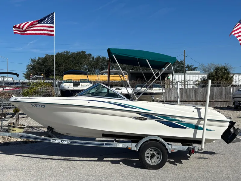Slide: The Image of 1998 Sea Ray 180 Bow Rider boat on trailer, with American flags in the background. - 2