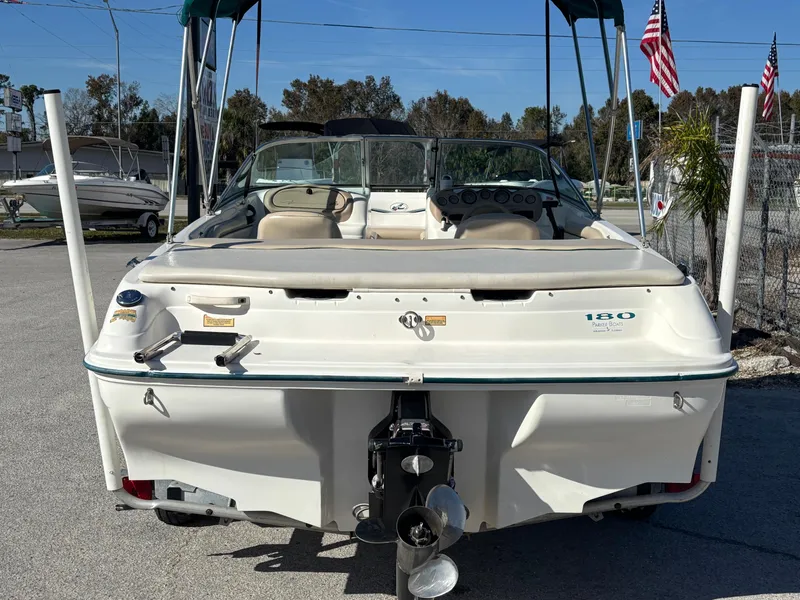 Slide: The Image of 1998 Sea Ray 180 Bow Rider boat, rear view, parked outdoors with flags in the background. - 5