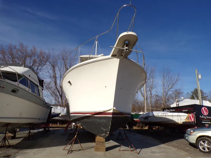 The Image of 1986 Jersey Dawn 40 boat on dry dock, surrounded by other vessels, under clear blue sky. - 1
