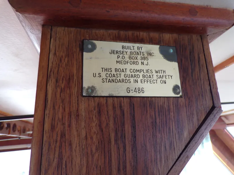 Slide: The Image of Plaque on 1986 Jersey Dawn 40 boat, indicating U.S. Coast Guard safety compliance. - 12