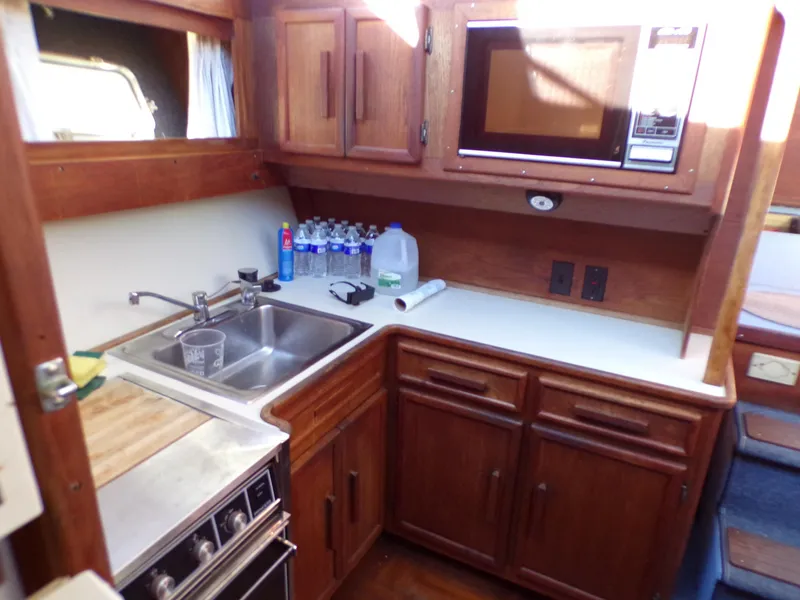 Slide: The Image of 1986 Jersey Dawn 40 yacht kitchen with wooden cabinets, sink, stove, and microwave. - 14