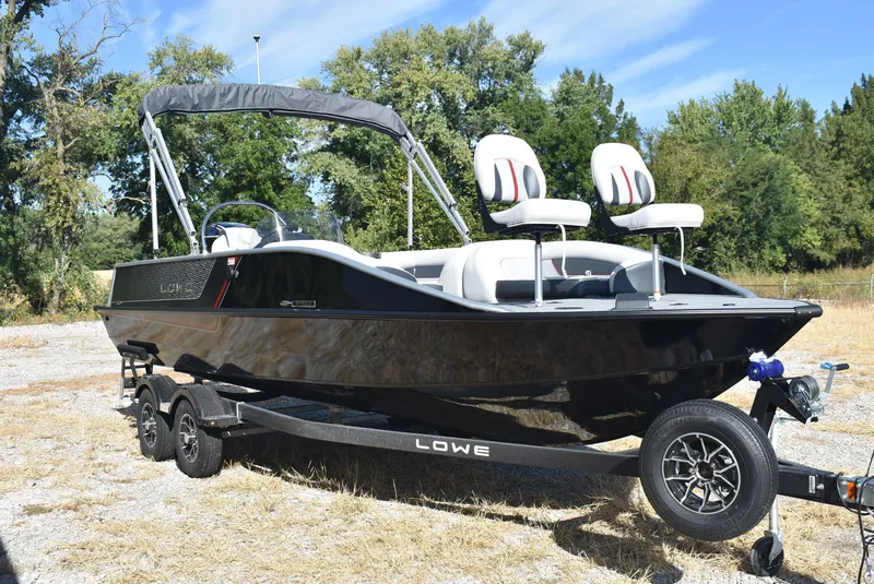 Slide: The Image of 2025 Lowe SD224 Sport Deck boat on trailer, parked outdoors. - 3