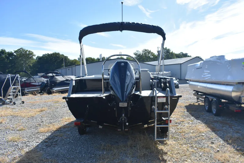 Slide: The Image of 2025 Lowe SD224 Sport Deck boat with outboard motor and ladder, parked outdoors. - 4