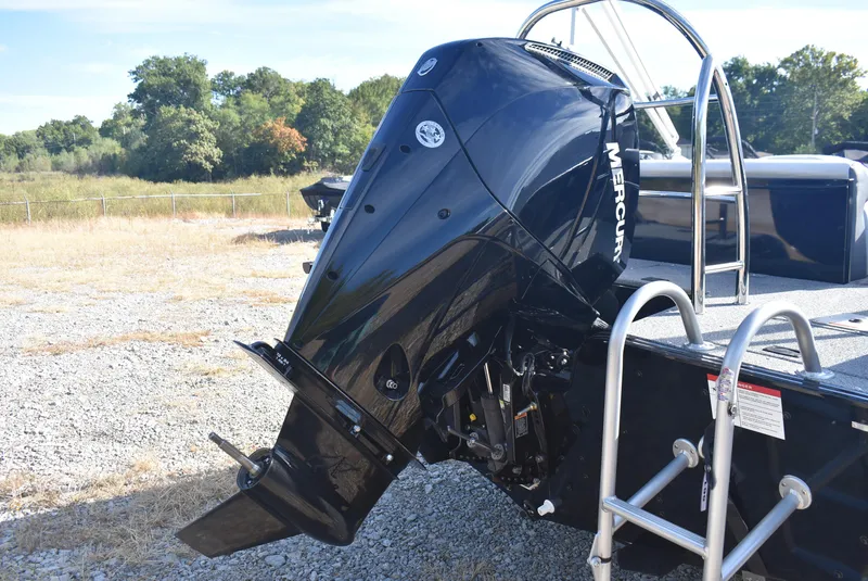 Slide: The Image of 2025 Lowe SD224 Sport Deck with Mercury outboard engine, parked on gravel. - 5