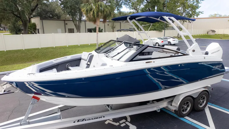 Slide: The Image of 2025 Cobalt R6 Outboard boat on trailer, blue and white design, parked outdoors. - 3