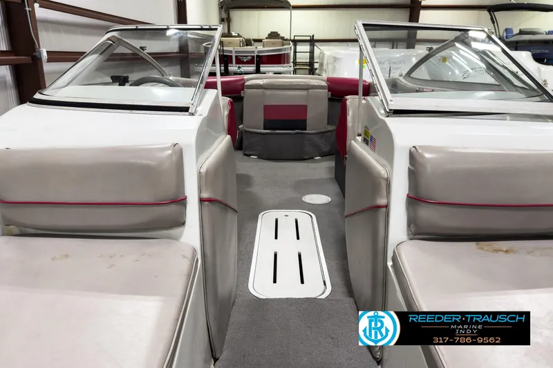 Slide: The Image of 1993 Bryant 200 boat interior with gray and red seating, displayed in a showroom. - 11